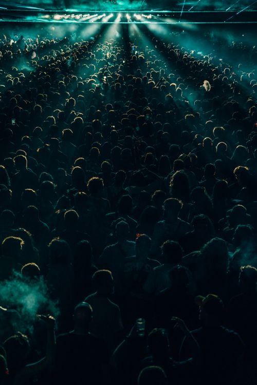 Epic stadium concert crowd under teal stage laser beam canopy