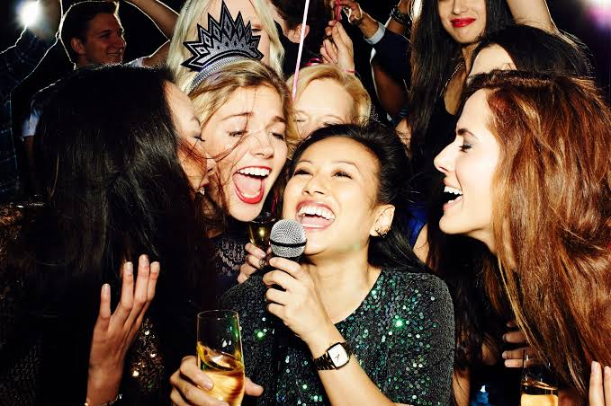 Group of friends singing karaoke and celebrating at live party